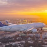 تصویری از هواپیمای در حال پرواز در آسمان و غروب آسمان زرد و نارنجی